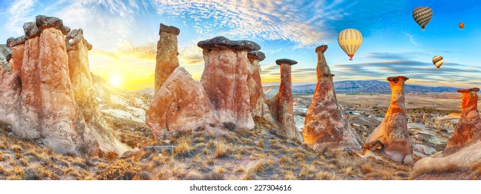 Rocks looking like mushrooms dramatically lit by a sunset in Cappadocia, Turkey. With balloons