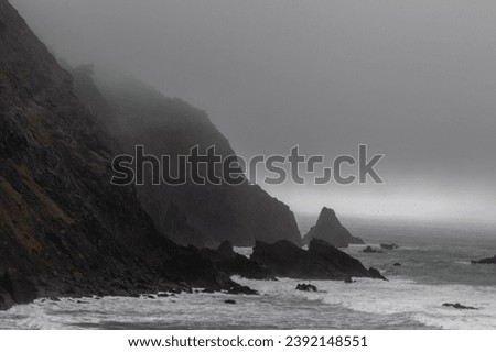 Rocks off route 101 coastal highway during a storm, Image shows the rough Pacific ocean swells hitting the cliffs and low level fog and mist covering the bay 