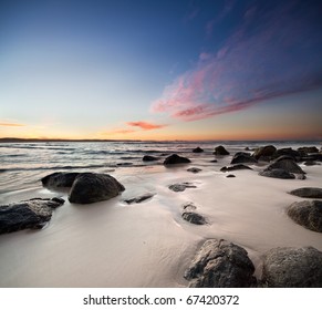rocks on the beach with red clouds on square format