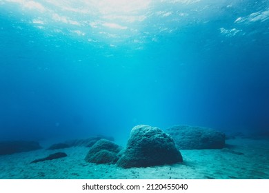 Rocks on sand at bottom of ocean floor in blue clear sea - Shutterstock ID 2120455040