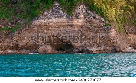 Rocks in the sea. Cliff with a grotto. A plot of rock on a tropical island by the sea. A rock by the sea with traces of weathering and erosion.                               
