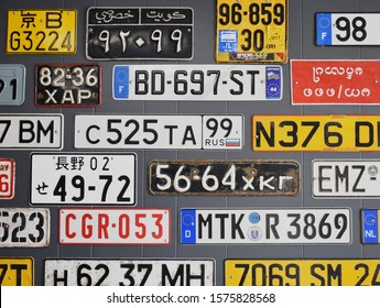 Rockville, Maryland, America - November 25, 2019: Many different license plates from all around the world displayed on the dark gray wall at auto service office. 