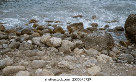 Rocky beach coastline with waves crashing on the pebbles and stones near the seashore in a serene outdoor setting. - Powered by Shutterstock