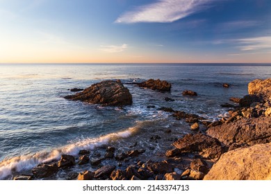 Rocky Beach In Malibu, California In Early Morning. Calm Pacific Ocean In The Distance; Blue Sky And Clouds Overhead.
