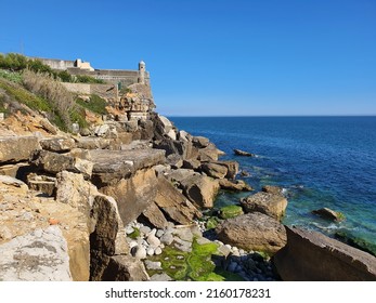 Rocky Beach And Medieval Fort Or Forte De Santo António Da Barra. Atlantic Ocean Shore And Blue Sky Background.