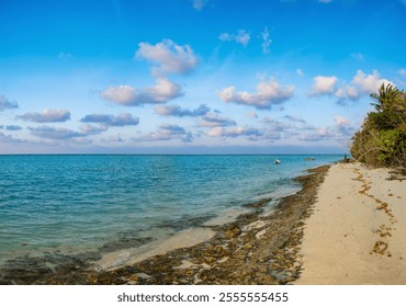 Rocky beach shore in evening, calm blue sea water with fisherman boats, sky with clouds and white sand. Tropical summer island beach in calm time of sunset, lonely silhouette of man in distance - Powered by Shutterstock