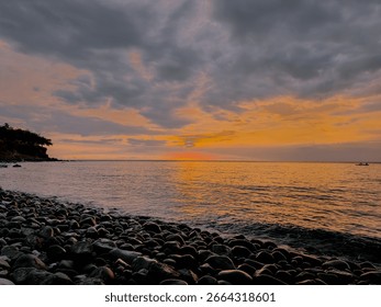 Rocky beach at sunset with dramatic clouds and warm orange tones reflecting on the calm sea. - Powered by Shutterstock - Get 15% off with code: PIKWIZARD15