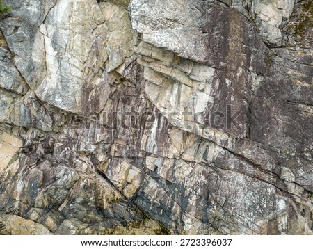 Rocky cliff with layered strata and angular fractures; a natural coastal scene. West Coast Shore in British Columbia, Canada