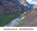 The rocky cliffs of Hells Canyon are reflected in the Snake River on the Idaho Oregon border north of Oxbow in Oregon, USA