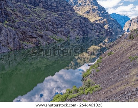 The rocky cliffs of Hells Canyon are reflected in the Snake River on the Idaho Oregon border north of Oxbow in Oregon, USA