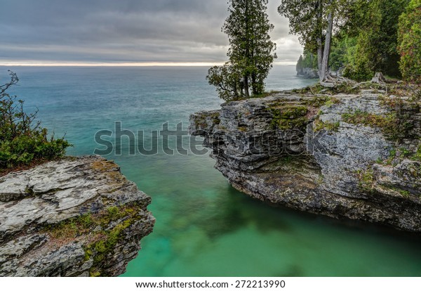 The\
rocky coast of Door County, Wisconsin\'s Cave Point displays\
beautiful colors in the light of a stormy\
sunrise.