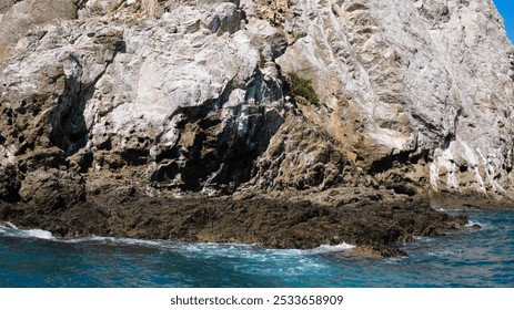 A Rocky coastal cliff with blue ocean water and clear sky in New Zealand - Powered by Shutterstock