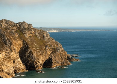 A rocky coastal cliff with mist surrounding the sea stacks in a serene afternoon light - Powered by Shutterstock