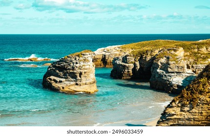 Rocky coastal cove with turquoise waters and lush greenery under clear sky .  - Powered by Shutterstock