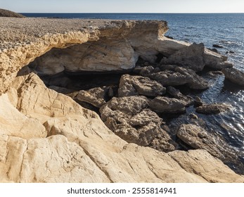 The rocky coastline of Cyprus, with smooth stones leading into the clear waters of the Mediterranean, creating a rugged and natural coastal landscape. - Powered by Shutterstock