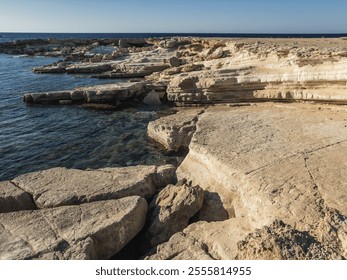 The rocky coastline of Cyprus, with smooth stones leading into the clear waters of the Mediterranean, creating a rugged and natural coastal landscape. - Powered by Shutterstock