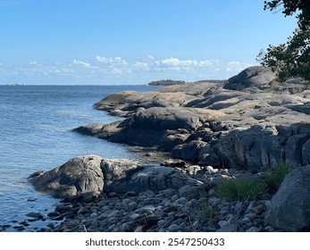 Rocky coastline of the Finnish archipelago on a sunny day. Clear blue water and rugged shoreline create a peaceful and scenic atmosphere, ideal for travel, adventure, and outdoor themes. - Powered by Shutterstock