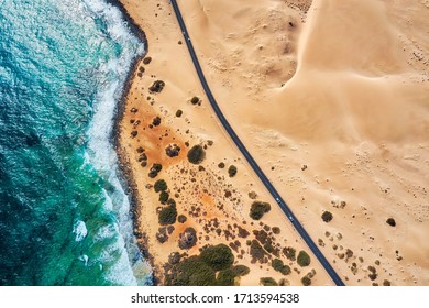 Rocky coastline and highway with golden sand and blue water - Powered by Shutterstock