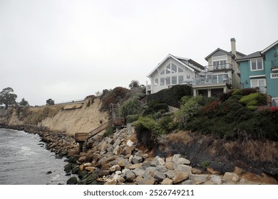 Rocky coastline with houses on the Pacific Ocean shore in foggy weather in Capitola California - Powered by Shutterstock