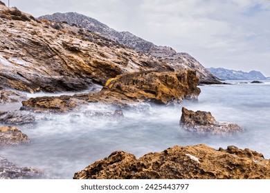 "Rocky coastline, misty waters, cloudy sky, serene and rugged." - Powered by Shutterstock