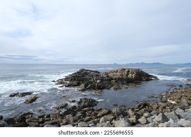 Rocky coastline of the ocean bay, cloudy sky 