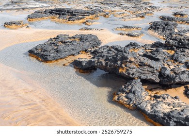 Rocky coastline and sandy beach. Picturesque beach with scattered rocks and clear water - Powered by Shutterstock