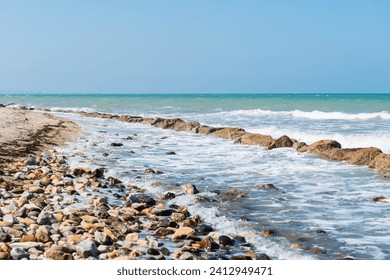 Rocky coastline. Sea wave background breaking sea water rocky shore rough turquoise water at Rimini, Italy. Seascape with sea horizon and clear deep blue sky. - Powered by Shutterstock
