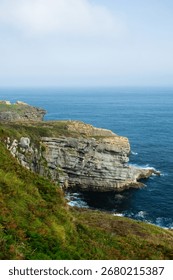 Rocky coastline with sharp cliffs and deep blue sea under a clear sky.