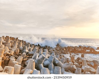 A rocky coastline at sunset with concrete wave breakers. Gentle waves crash against the shore, capturing nature's beauty and strength. Perfect for coastal themes. - Powered by Shutterstock