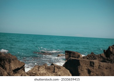 A Rocky coastline with turquoise sea and clear blue sky on a sunny day - Powered by Shutterstock