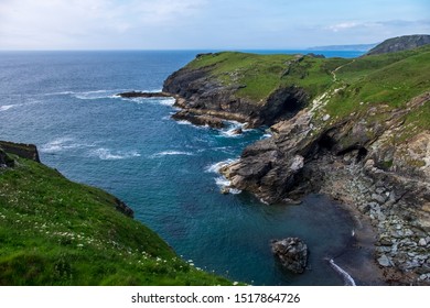 Rocky And Grass Cliffs Overlooking The Sea On A Partially Cloudy Day In England, UK.