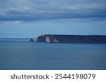 The rocky headland and the lighthouse at the Cap of Sao Vicente at the south-west end of Europe, open sea to the Atlantic Ocean. View from the fortress Sagres, Algarve, Portugal.