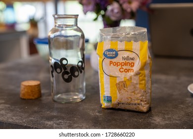 Rocky Hill, CT, USA - May 6, 2020 - Bag of Great Value brand Popcorn plastic bag waiting to be poured into glass jar. 