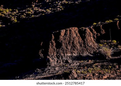 A rocky hillside with a dark shadow cast over it. The shadow is large and extends across the entire hill - Powered by Shutterstock