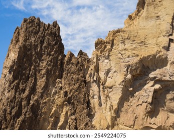 A rocky mountain with a clear blue sky in the background. The mountain is covered in rocks and has a rugged appearance - Powered by Shutterstock