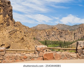 A rocky mountain range with a clear blue sky. The mountains are covered in brown rocks and the sky is filled with clouds - Powered by Shutterstock