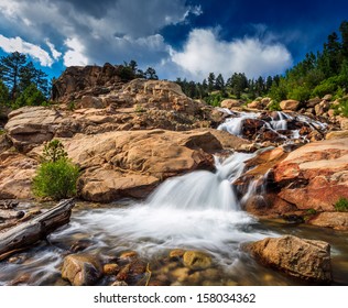 Rocky Mountains national park, glacier waterfall in daylight with clouds.