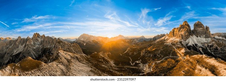 Rocky mountains rise above deep canyons. Mountain landscapes of primeval nature under blue sky. Tre Cime di Lavaredo at sunset aerial view - Powered by Shutterstock