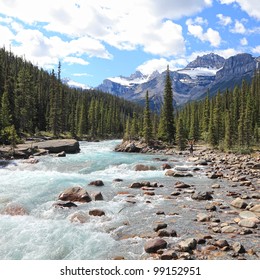 Rocky Mountains And River With A Rapids Flowing In A Valley Between Mountain Wood In Jasper National Park (Alberta, Canada)