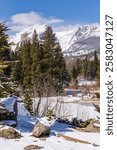 Rocky Mountains from Sprague Lake in Colorado.  Snow and ice on a lake in the Rocky Mountains of Colorado. Hallett Peak in the background with trees and scrub in foreground. 