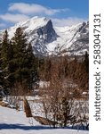 Rocky Mountains from Sprague Lake in Colorado.  Snow and ice on a lake in the Rocky Mountains of Colorado. Hallett Peak in the background with trees and scrub in foreground. 