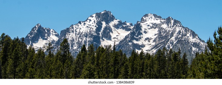 The Rocky Mountains In Wyoming With Evergreen Treeline In The Foreground.