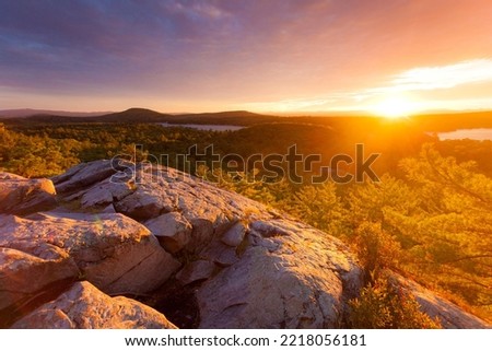 Rocky mountaintop overlooking Lake Dunmore and forest at sunset during autumn