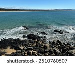 Rocky Oceanside, Rocky shoreline beach on sunny day, waves on rocks with rockpool and deep blue ocean.