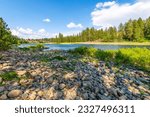 The rocky riverbank and shoreline of the Spokane River as it runs through the small town of Post Falls, Idaho, at McGuire Park.