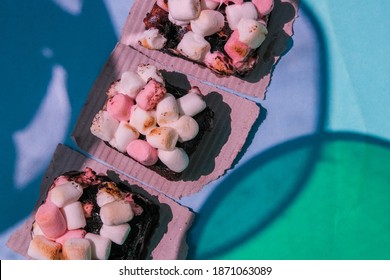 Rocky Road Brownies With Marshmallows On Blue Background With Colorful Shadows