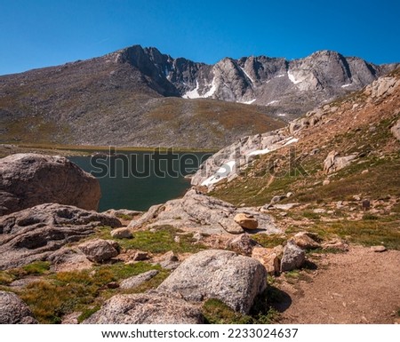 The rocky rugged shoreline of Summit Lake on Mount Evans, Colorado beneath a summer sky.