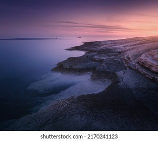 Rocky sea coast and lighthouse at colorful sunset in summer. Beautiful landscape with beach, stones in blurred blue water, purple sky at dusk. Nature. Adriatic sea at night, Kamenjak, Croatia. Travel - Powered by Shutterstock