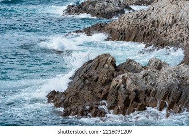 rocky seashore formed by columnar basalt against the stormy sea, coastal landscape of the Kuril Islands