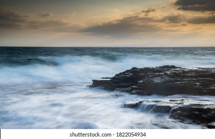 Rocky seashore with wavy ocean and waves crashing on the rocks at sunset. Larnaca coast area in Limassol, Cyprus - Powered by Shutterstock